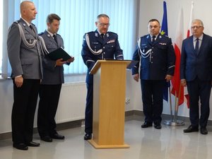 Komendant Powiatowy Policji w Łańcucie stoi przy mównicy i wygłasza okolicznościowe przemówienie. Obok niego stoi Zastępca Komendanta Wojewódzkiego Policji w Rzeszowie oraz Poseł na Sejm RP Kazimierz Gołojuch.