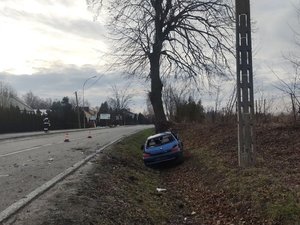 Obok jezdni, w przydrożnym rowie, znajduje się samochód marki Peugeot. Samochód ma rozbitą tylną szybę.