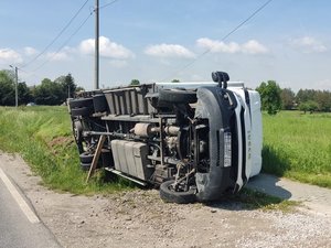 Pojazd marki Iveco leży na chodniku na lewym boku. Tył samochodu znajduje się częściowo na przydrożnym rowem.