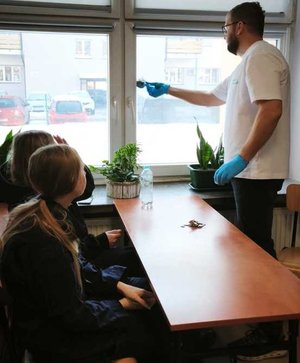 Policyjny technik za pomocą pędzelka ujawnia ślady odcisków palców na szybie.
