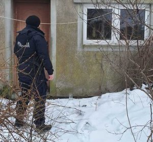 Funkcjonariusz rewiru dzielnicowych stoi przed drzwiami do budynku mieszkalnego.