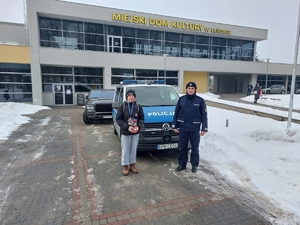 Wolontariusz WOŚP z policjantem stoją przed radiowozem.