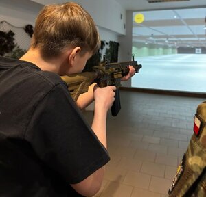 Uczestnik zawodów strzela z karabinu na wirtualnej strzelnicy.