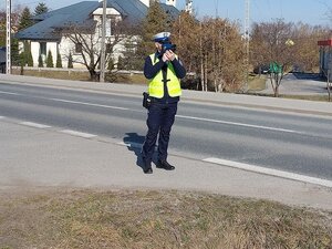 Policjant trzyma w rękach miernik prędkości.