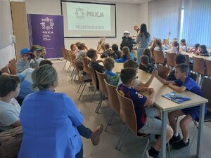 Policjant pomaga uczennicy ubrać policyjny zastaw przeciwuderzeniowy.