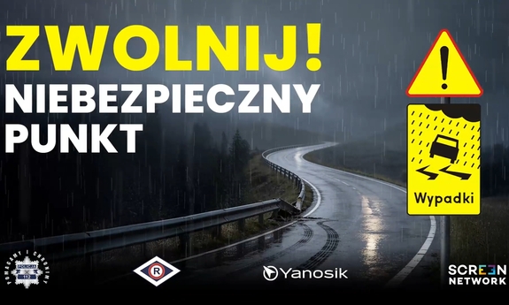 Plakat informacyjny z napisem: Zwolnij! Niebezpieczny punkt. W tle kręta droga.