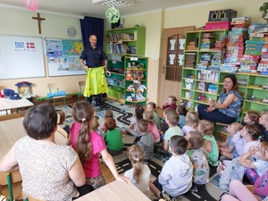 Funkcjonariusz rewiru dzielnicowych rozmawia z dziećmi na temat bezpieczeństwa podczas zbliżających się wakacji.
