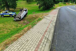 Leżący na dachu, poza jezdnią, pojazd marki Honda.
