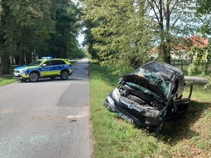 W przydrożnym rowie stoi uszkodzony pojazd marki Honda. Na drodze stoi oznakowany radiowóz.