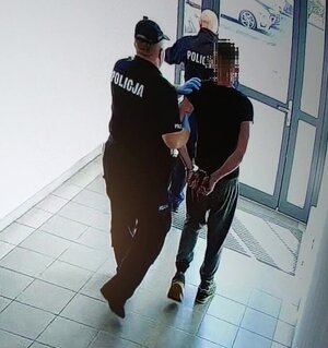 Policjanci prowadzą zatrzymanego podpalacza